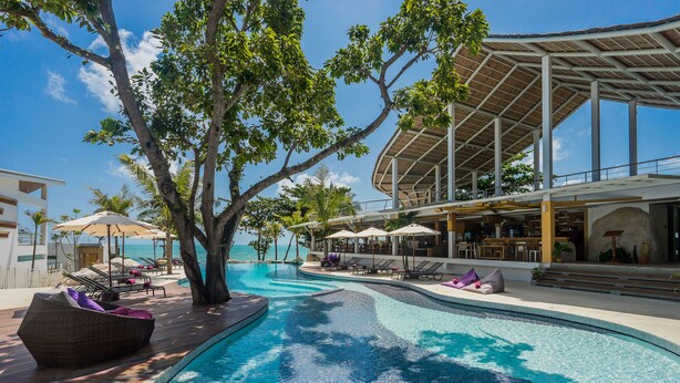 A pool area with lounge chairs and umbrellas, a covered seating area, and a view of the ocean. - White Sand Samui Resort (Koh Samui)
