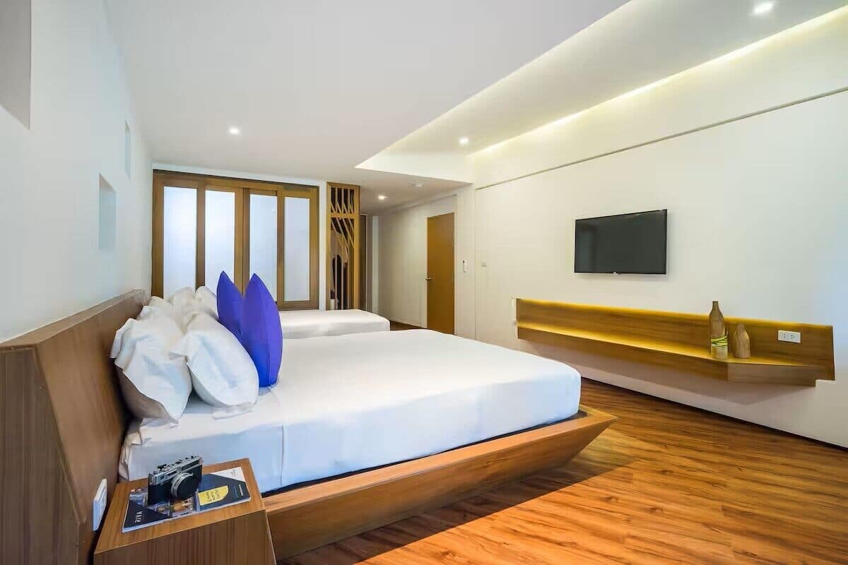 Un dormitorio moderno con una cama, un televisor y una estantería de madera.
