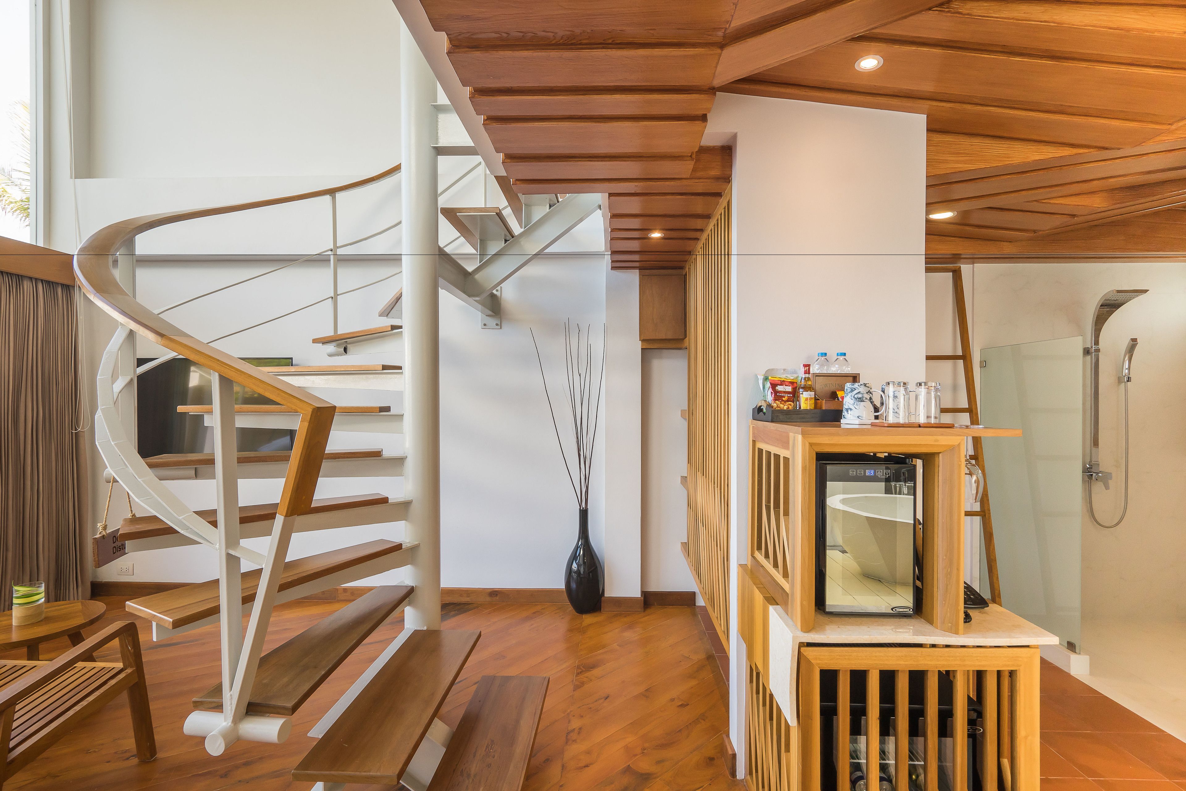A modern interior with a wooden staircase, a compact kitchenette, and a glass shower area.