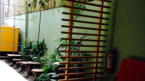 Un interior moderno con un sofá rojo, un separador de madera con listones y una pared verde con plantas.
