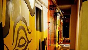 Un pasillo con un mural grande y estilizado en la pared y un piso con la palabra 'HOTEL' pintada en letras grandes.