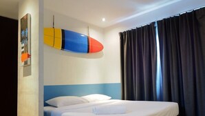Una habitación de hotel con una cama, una tabla de surf colgada en la pared y un ventanal con cortinas.