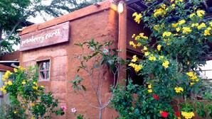 A rustic building with a sign reading "pranberry earth" and a variety of flowering plants. - Pranberry Earth (Pranburi)