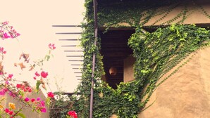A building with a textured exterior wall, a small window, and a hanging basket. - Pranberry Earth (Pranburi)