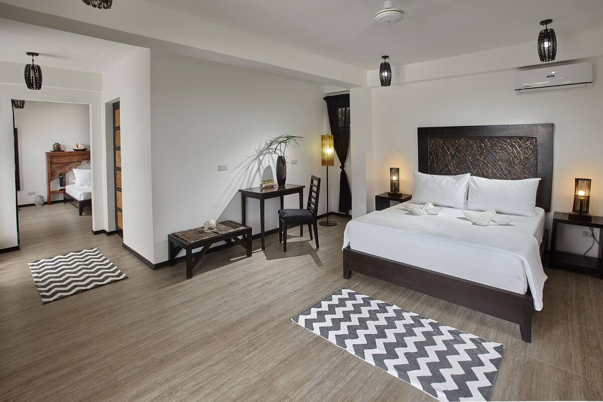 Una habitación de hotel moderna con una cama grande, mesitas de noche, un escritorio y una silla.