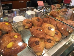 Vitrine com diversos doces, incluindo croissants e pastéis recheados.
