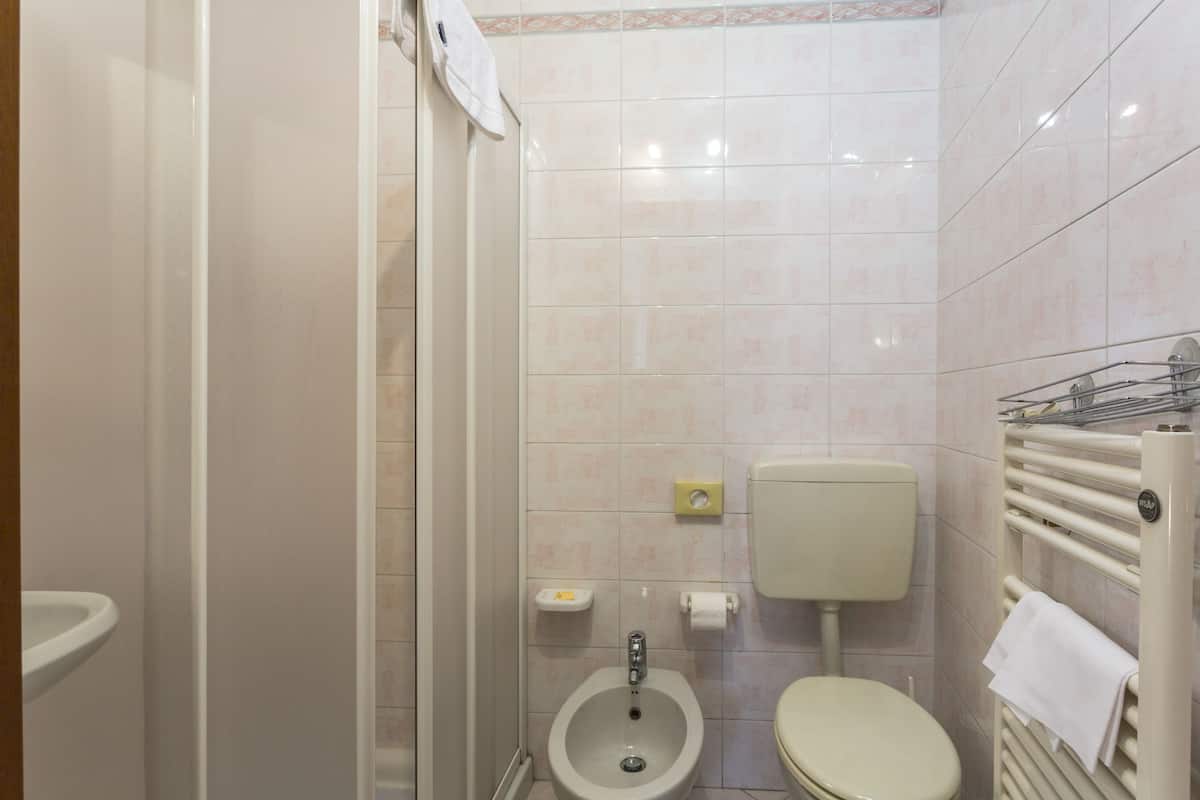 Ein kleines, sauberes Badezimmer mit Toilette, Bidet und Handtuchhalter.