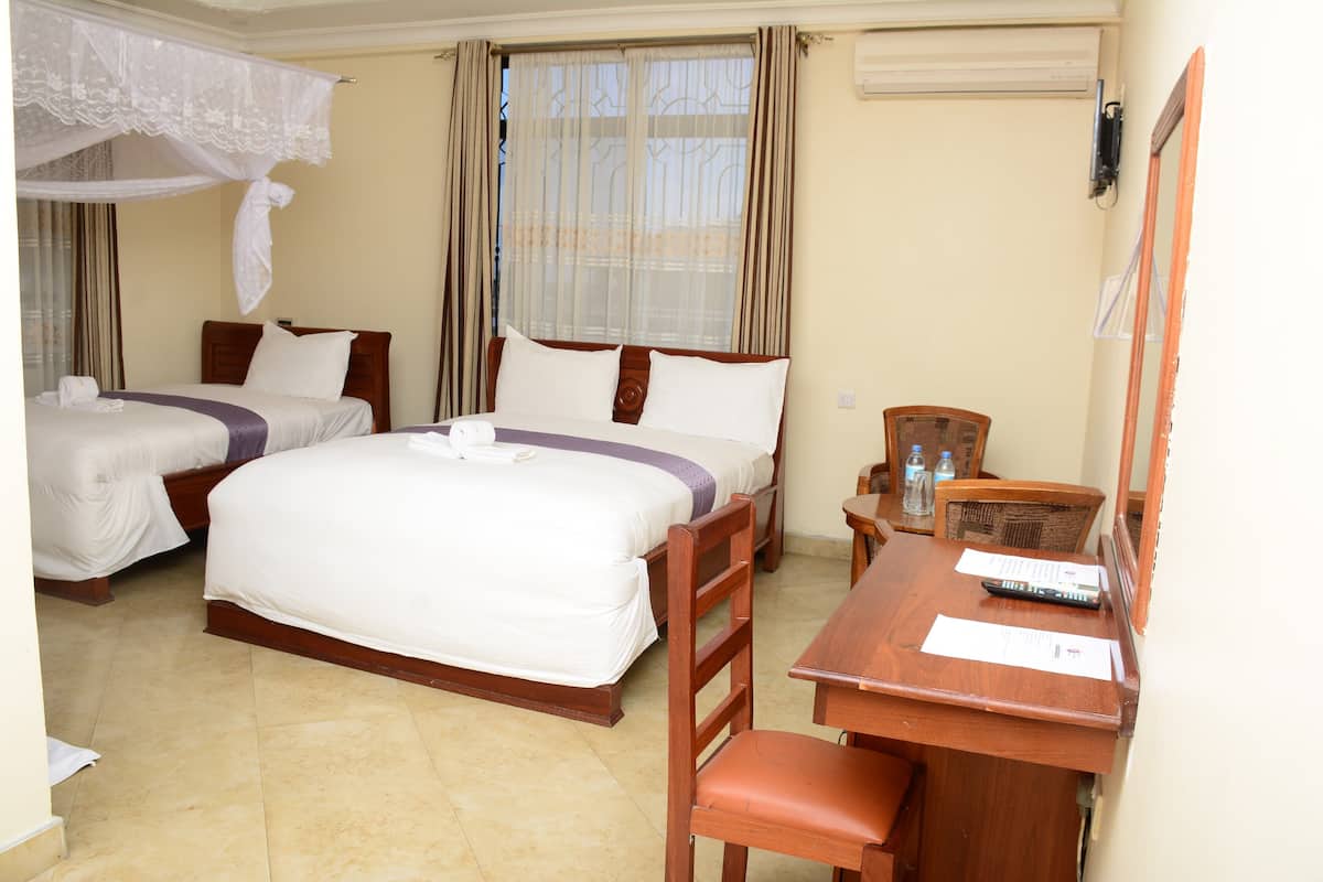 A hotel room with two beds, a desk with a chair, a mirror, and a window with curtains.