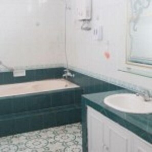A bathroom with a bathtub, a sink, and a mirror. - Simply Homy Tubagus Dago (Bandung)