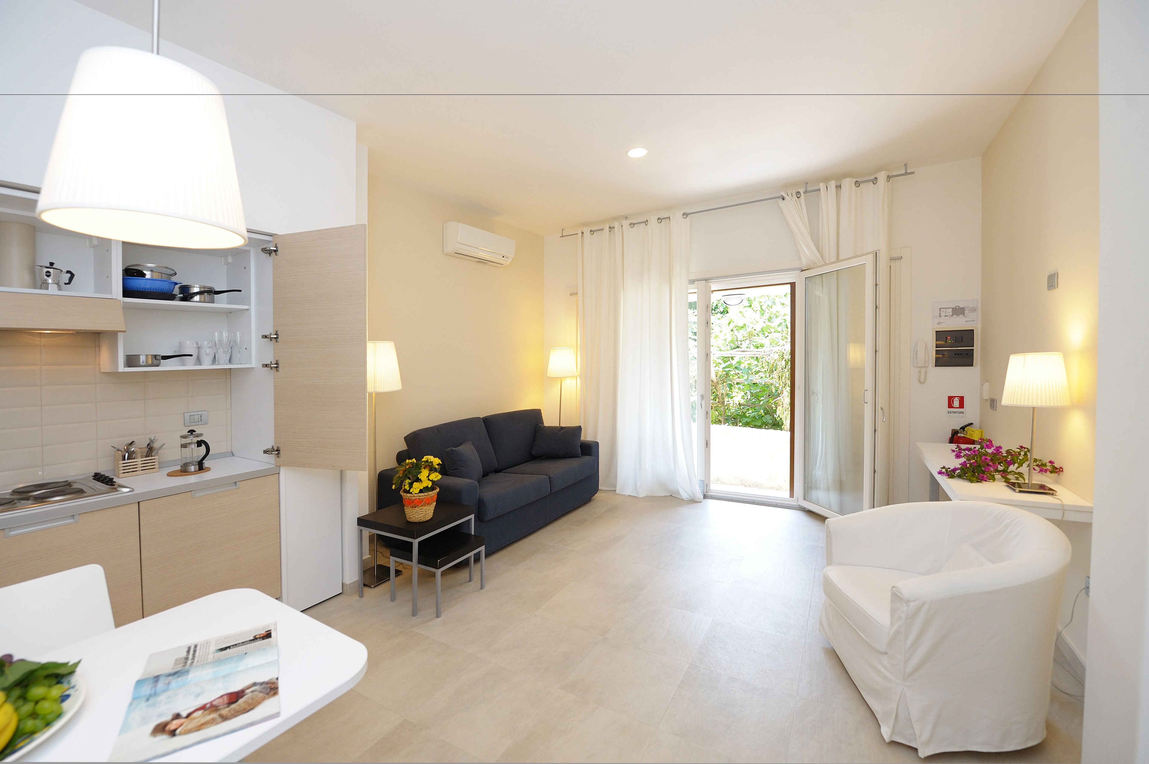 Una sala de estar moderna con sofá, una mesa de comedor y una zona de cocina con armarios y un fregadero.