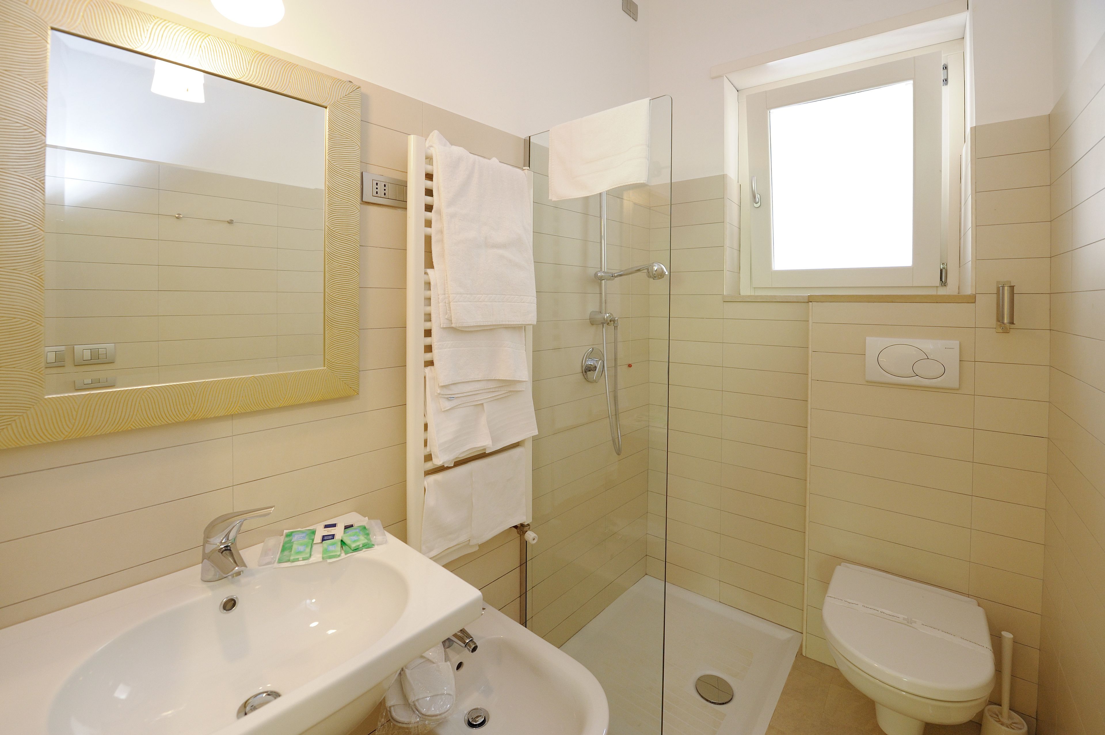 A bathroom with a sink, mirror, glass-enclosed shower, and toilet.