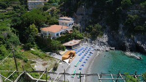 Ein Küsteneigentum mit Strand, einer Holzterrasse und Blick auf eine Klippe.