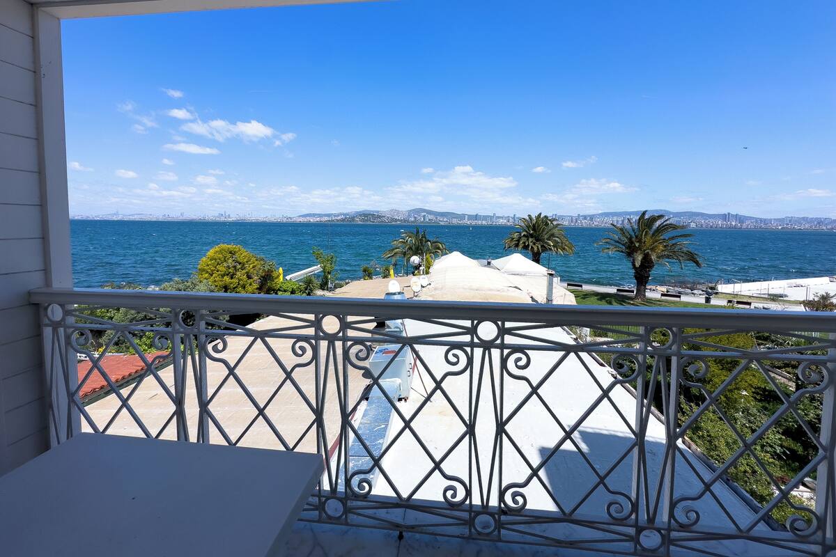 A balcony with a view of the sea and a city skyline.