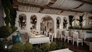 A restaurant with white tables and chairs, arches, and greenery. - Buyukada Port Hotel (Adalar)