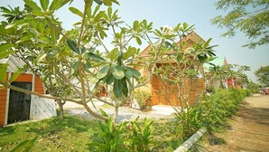 A bungalow with a wooden exterior, surrounded by lush greenery and a dirt path. - Tonrak Resort (Ongkharak)