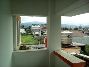 A view from a window overlooking a residential area with houses, a satellite dish, and a water tank.