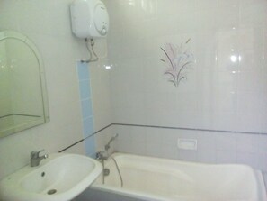 A bathroom with a sink, a mirror, a wall-mounted soap dispenser, and a decorative tile design.
