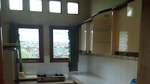 Una cocina con armarios blancos, suelo de baldosas y una ventana con cortinas.