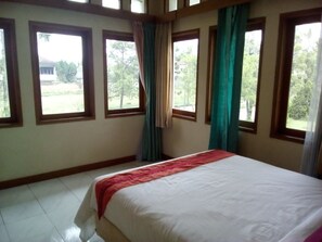 A bedroom with a bed, large windows, and curtains. - Simply Homy Guesthouse Graha Puspa (Parongpong)