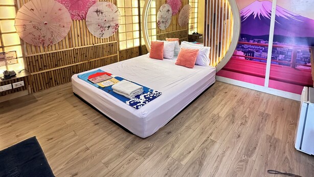 Un dormitorio moderno con cama, suelo de madera y una pared decorativa con un espejo circular.
