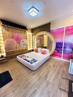 A modern bedroom with a bed, wooden floor, and a decorative wall with a circular mirror. - Honey Inn (Lam Luk Ka)
