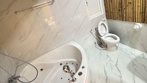 Un baño con suelo de mármol, bañera con ducha integrada, inodoro y pared de bambú.
