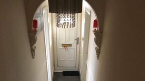 A narrow hallway with a door at the end, a doormat, and a small rug on the floor. - Icon Gorleston Apartment (Great Yarmouth)
