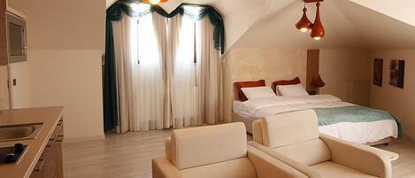 A bedroom with a bed, two bedside tables, a sofa, and a window with curtains.