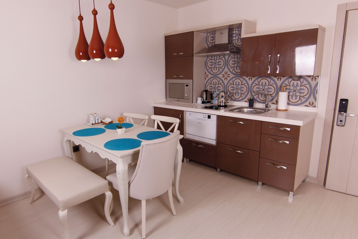 Uma cozinha compacta com mesa, cadeiras, micro-ondas, pia e máquina de lavar louça.