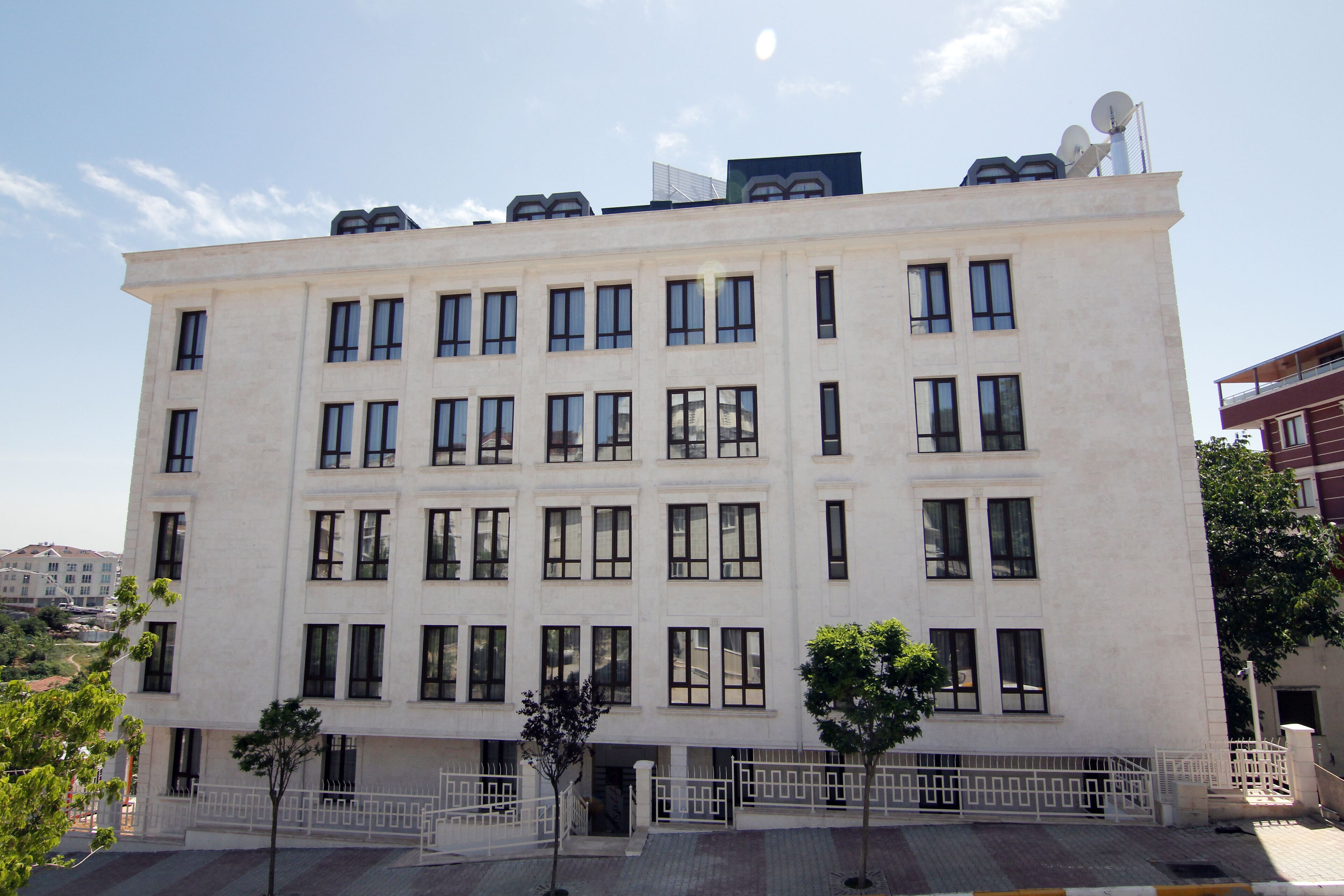 A multi-story building with a symmetrical facade, large windows, and satellite dishes on the roof.