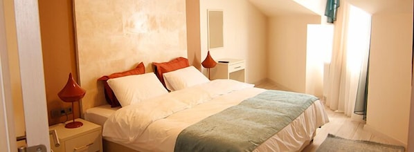 A bedroom with a bed, bedside tables, a desk, and a mirror.