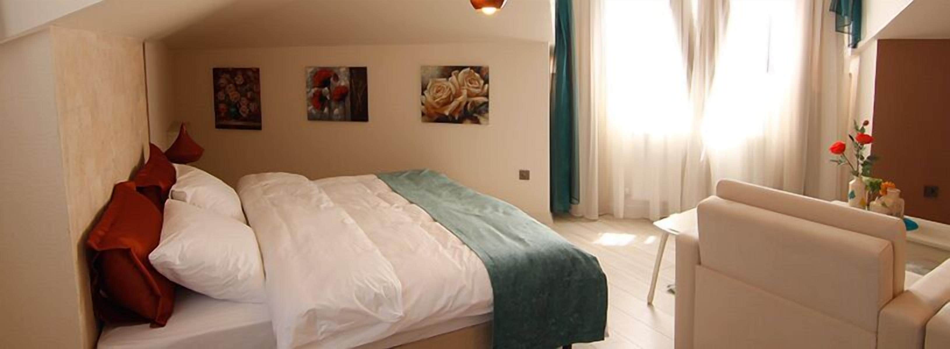 Een slaapkamer met een bed, een stoel en drie schilderijen aan de muur.
