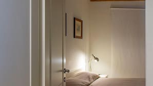 A bedroom with a wooden ceiling, a bed, a bedside lamp, and a door. - Cà Farnese (Venice)