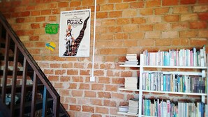 A brick wall with a poster, a staircase, and a bookshelf filled with books. - The Soul (Wenshan)