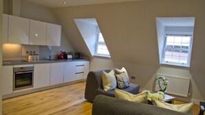 Un apartamento moderno con cocina, un sofá gris y una mesa de comedor.