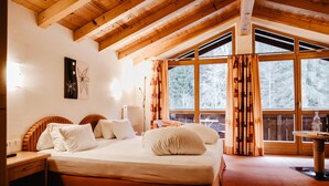 A bedroom with a large bed, wooden headboard, a bedside table, a nightstand, and a window with curtains.