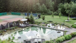 A swimming pool with a wooden deck, lounge chairs, and an umbrella.