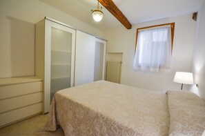 A bedroom with a bed, a wardrobe, a radiator, and a window with curtains. - Cà Marin (Venice)