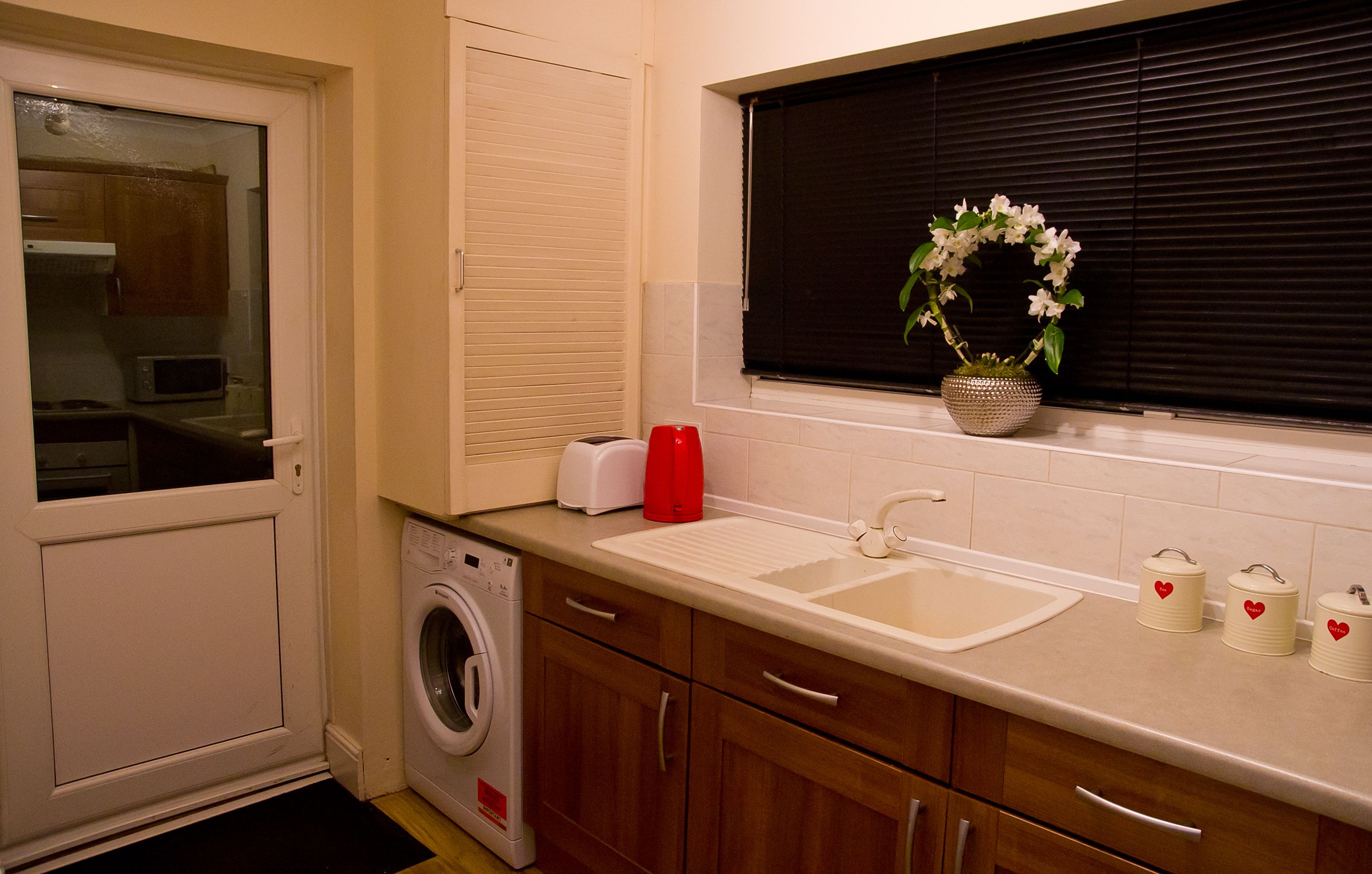 A compact kitchen with a washing machine, a toaster, and a sink.