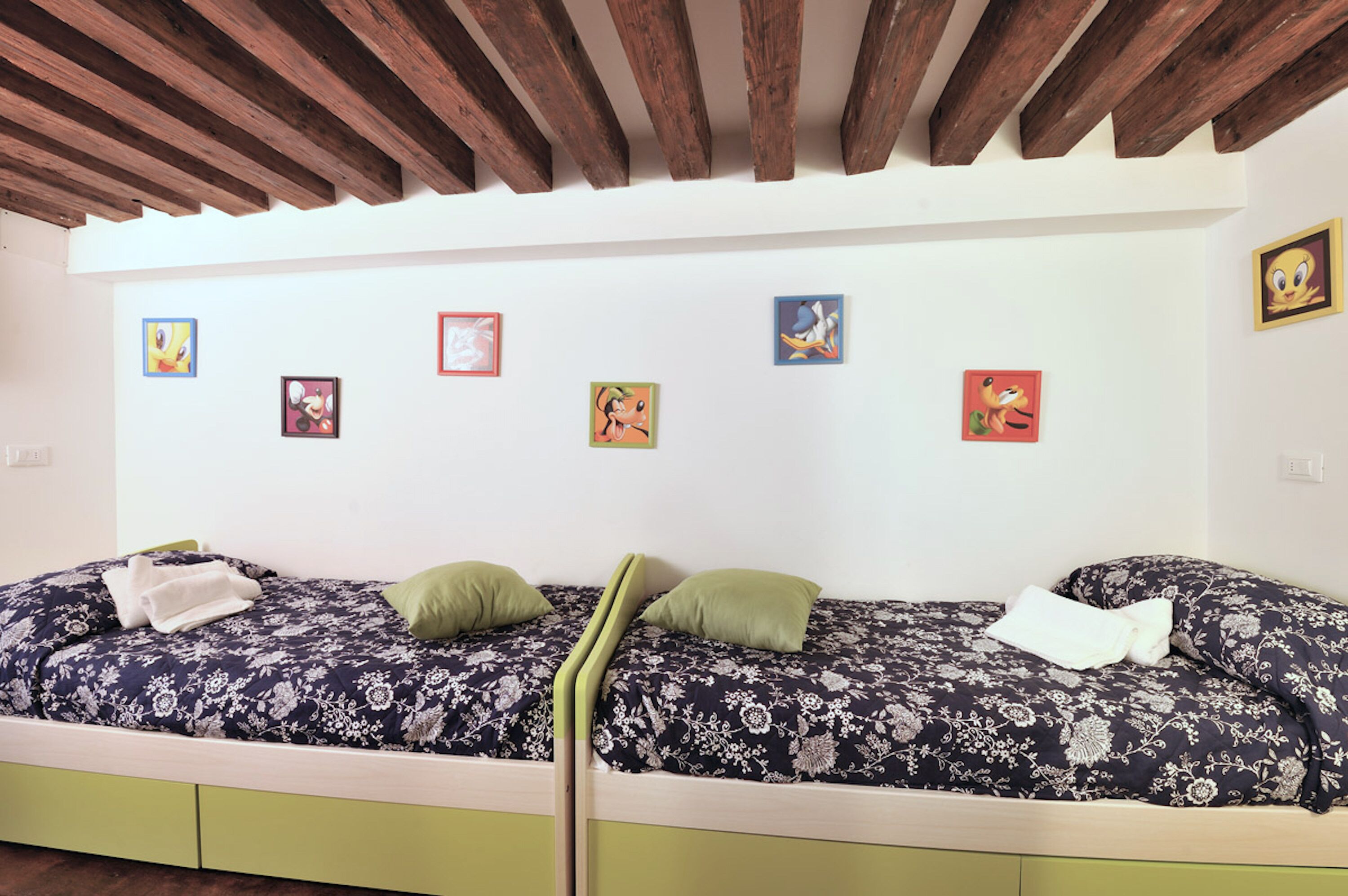 Un lit double avec une literie à motifs floraux, deux oreillers et une tête de lit en bois.