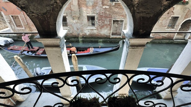 Una scena di un canale con barche, un ponte e edifici sullo sfondo.