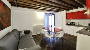Una cucina moderna con mobili rossi, un tavolo da pranzo con sedie bianche e un soffitto in legno.