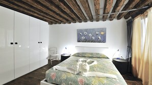 Una camera da letto con soffitto in legno, un letto con biancheria da letto a motivi floreali, un quadro appeso alla parete e un armadio.