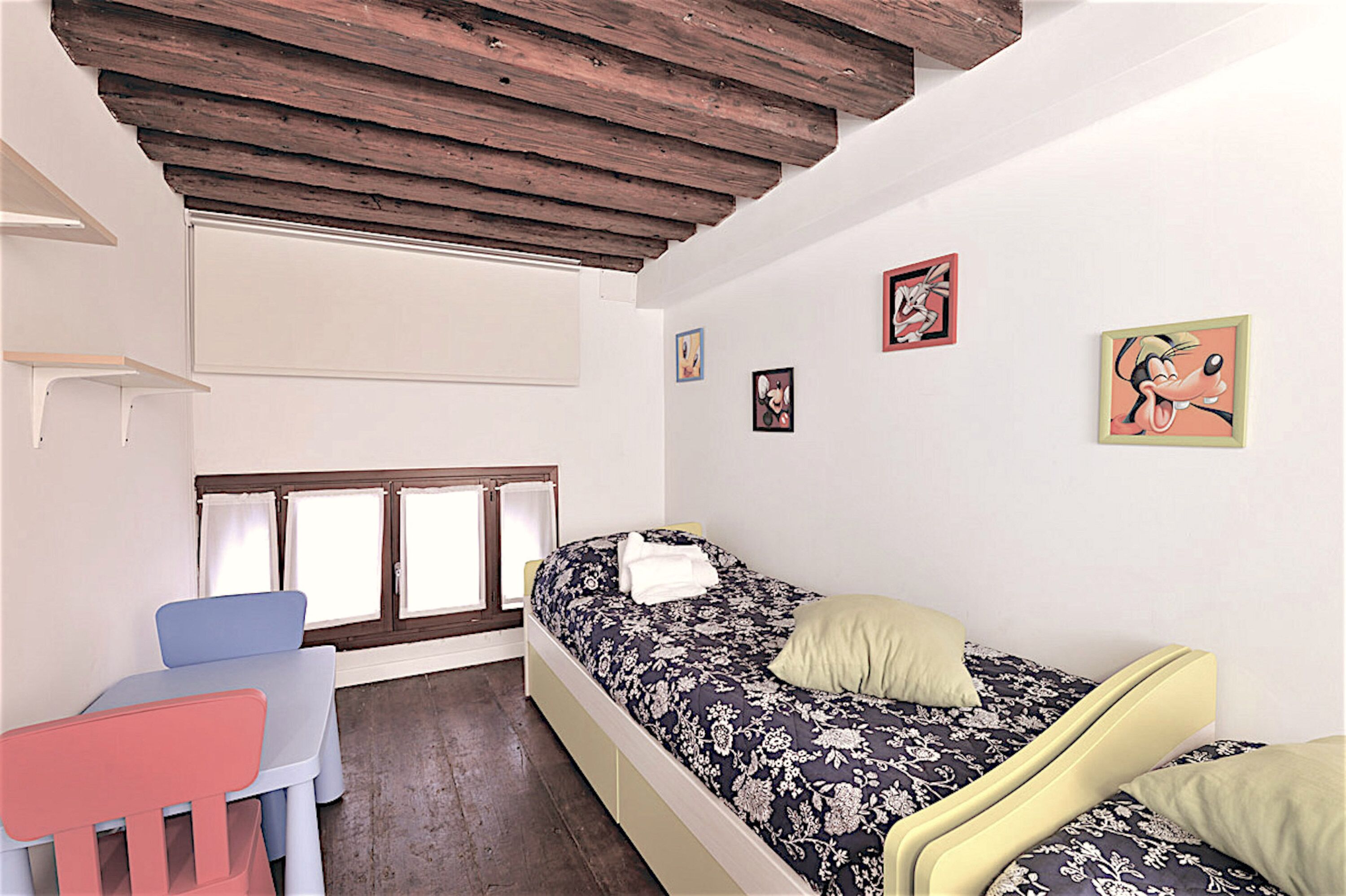 Un dormitorio con cama, escritorio y sillas.