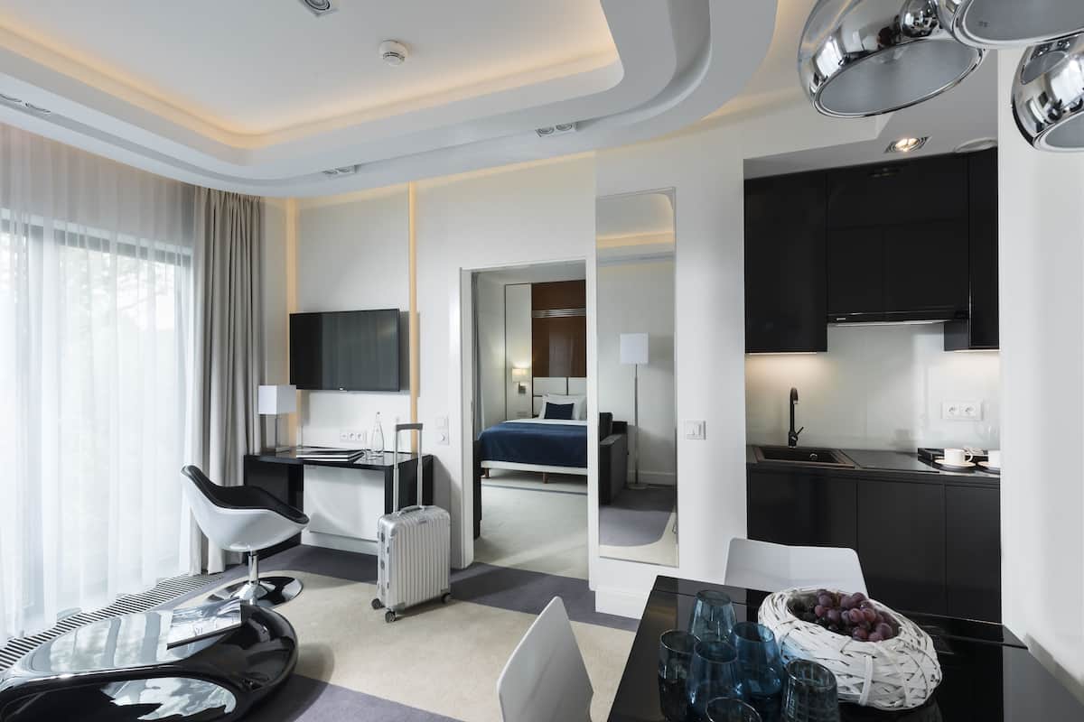 Ein modernes Hotelzimmer mit Schreibtisch, Stuhl, Bett und einer Küchenzeile.