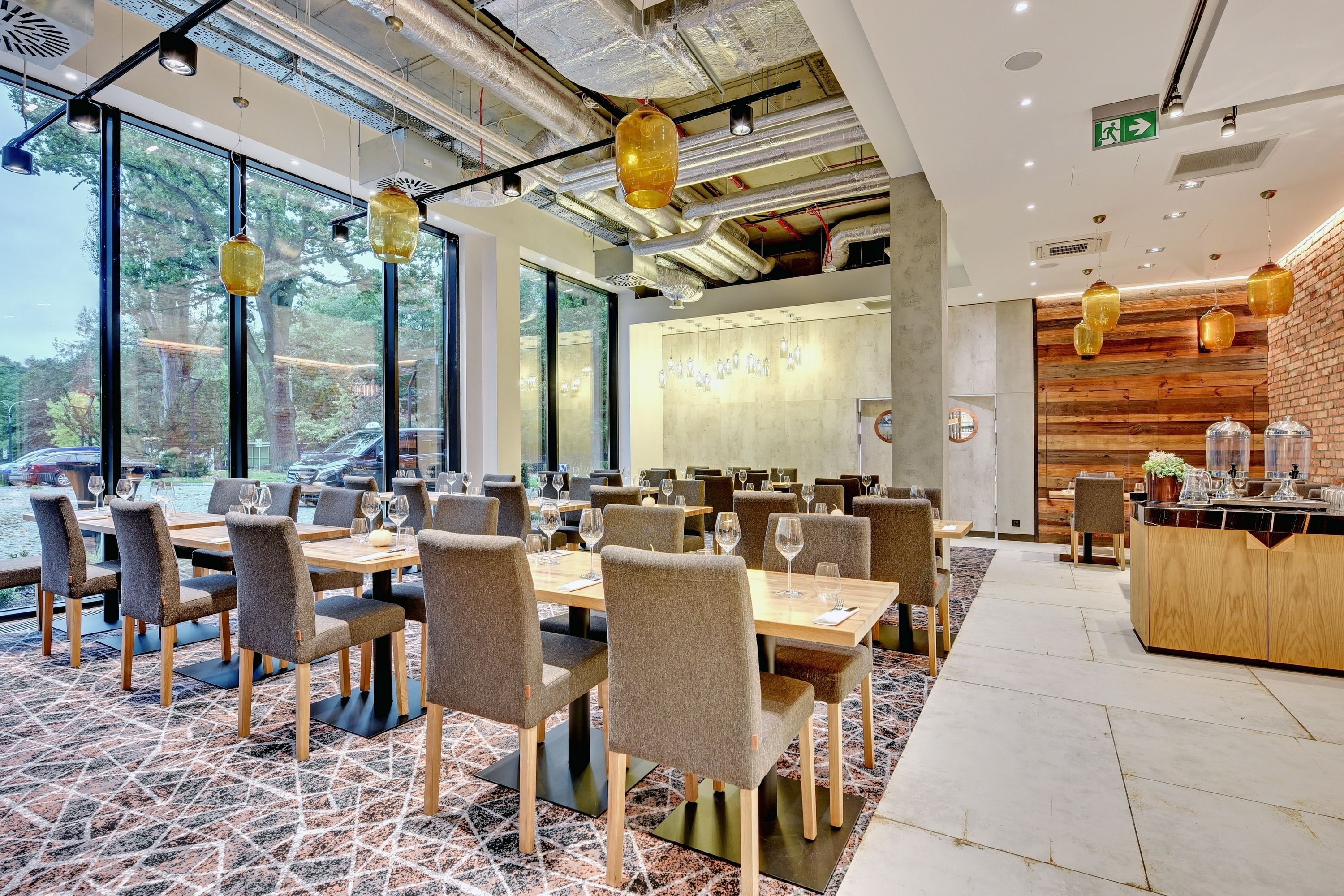 Een modern restaurant met grote ramen, houten tafels en hangende lantaarns.