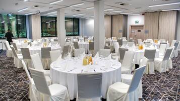 A conference room with round tables, white chairs, and a carpeted floor.