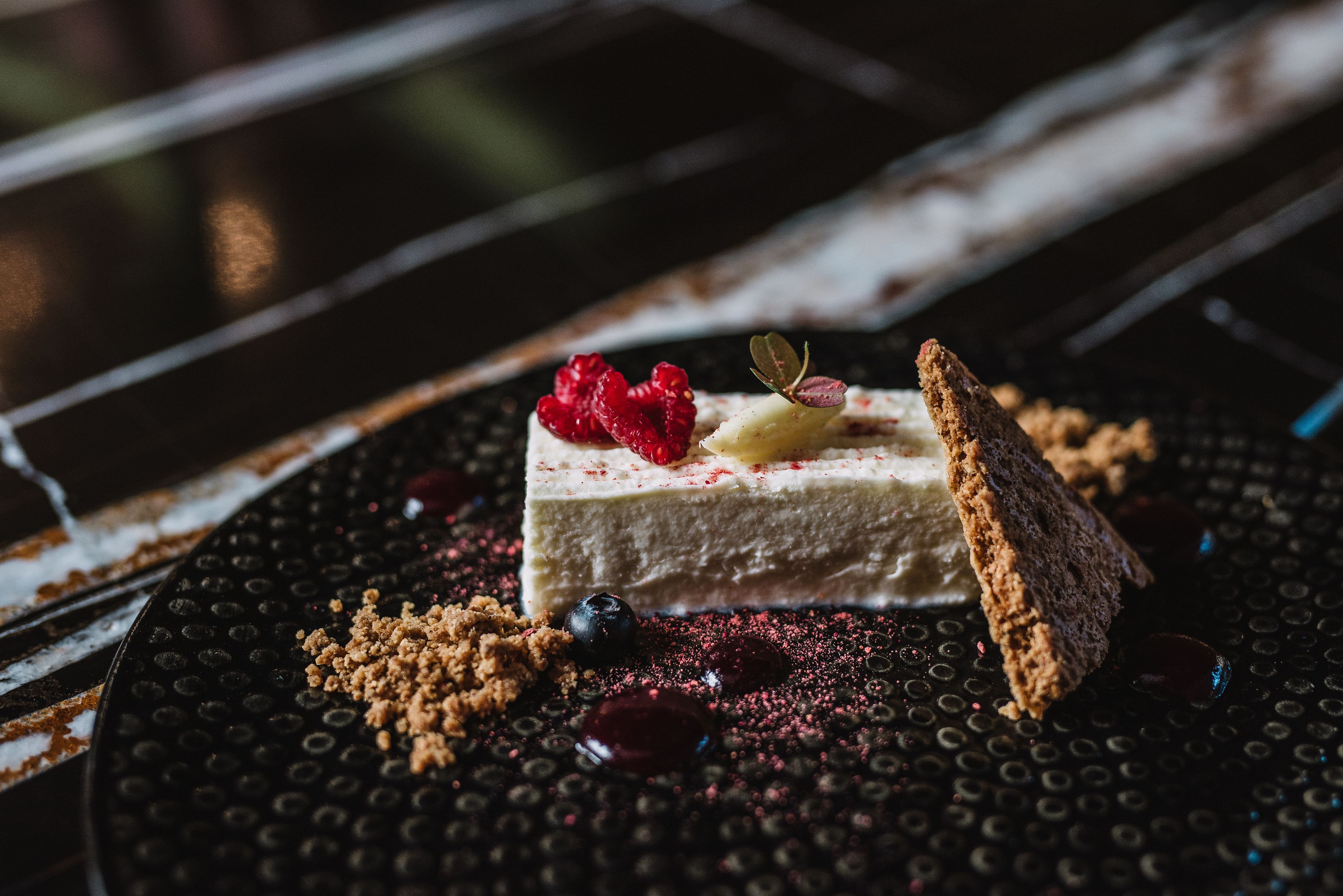 A dessert on a textured plate with berries and a piece of bread.
