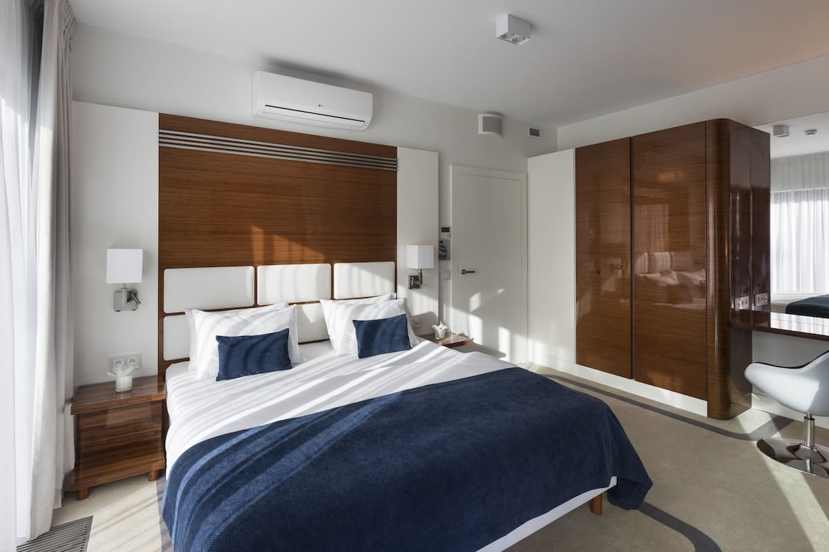 Ein modernes Hotelzimmer mit einem großen Bett, einem Holzkopfstütze und einem Kleiderschrank.