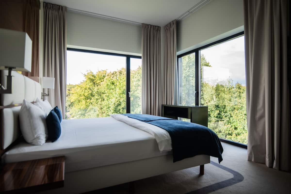 Ein modernes Hotelzimmer mit einem großen Bett, einem Schreibtisch und Blick ins Freie.